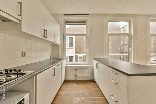an empty kitchen with white cabinets and black counter tops in front of the window looking out to the street outside