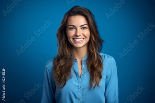 Medium shot portrait photography of a grinning girl in her 30s wearing an elegant long-sleeve shirt against a sapphire blue background. With generative AI technology © Markus Schröder