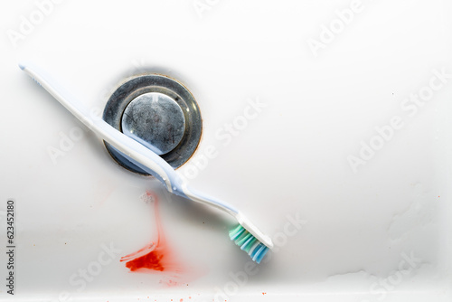 Toothbrush in a white washbasin with blood. Problem with gums