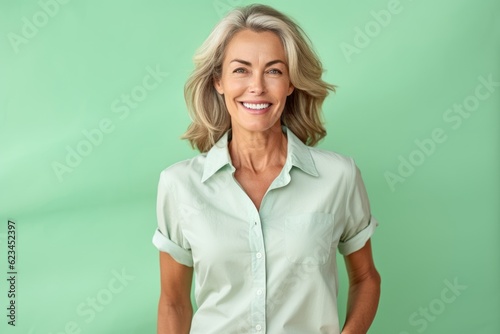 Lifestyle portrait photography of a beautiful mature woman wearing a casual short-sleeve shirt against a spearmint green background. With generative AI technology