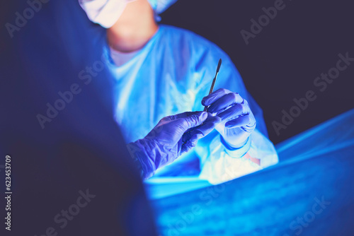 Doctor performing surgery in a dark background.