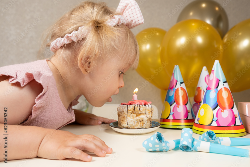 A two-year-old girl blows out a candle on a birthday cake, makes a wish