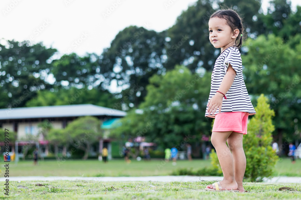 Happy Asian child in park standing with arms outstretched Young girl relaxing outdoors. Freedom concept.