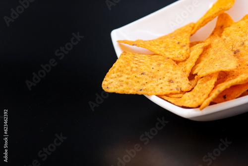mexican nachos in a bowl on black background with copy space