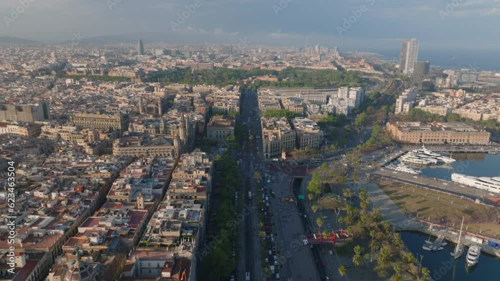 Forwards fly high above metropolis lit by low sun in late afternoon. Blocks of buildings and palaces with towers. busy multilane roads in city. Barcelona, Spain Forwards fly high above metropolis lit by low sun in late afternoon. Blocks of buildings and palaces with towers. busy multilane roads in city. Barcelona, Spain