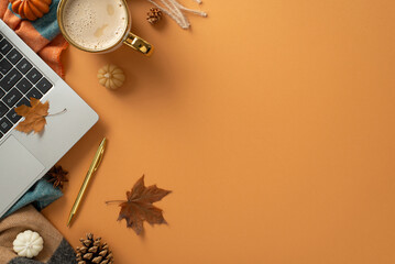 Freelance work in autumn concept. Top view photo of laptop, pen, a cup of coffee, patchy scarf and decor of pumpkin candles, maple leaves and pinecones on brown isolated background with copy-space