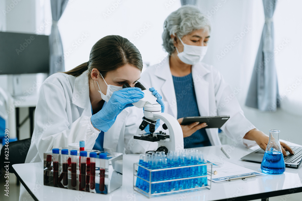 Two scientist or medical technician working, having a medical discuss meeting with an Asian senior female scientist supervisor in the laboratory with online reading, test samples and innovation Two scientist or medical technician working, having a medical discuss meeting with an Asian senior female scientist supervisor in the laboratory with online reading, test samples and innovation