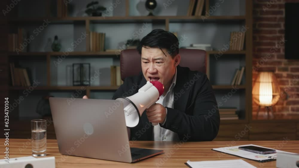 Annoyed asian entrepreneur getting acoustic megaphone from under table and yelling at employees. Angry man being dissatisfied with colleagues work and shouting during video conference. Annoyed asian entrepreneur getting acoustic megaphone from under table and yelling at employees. Angry man being dissatisfied with colleagues work and shouting during video conference.