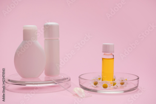 Mockup white bottles and transparent glass vial with essential oil with organic cosmetic products, for skin and body care from natural herbal and floral ingredients on pink isolated studio background