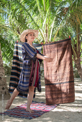 A young Asian woman used traditional ethnic Indonesian woven cloth against the backdrop of woven cloth and the beach