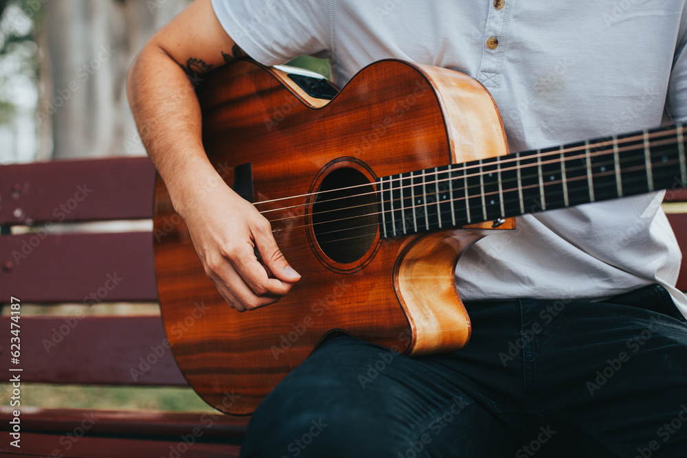 Fototapeta premium detail photograph of young man playing acoustic guitar outdoors. Concept of people, musicians and hobbies.