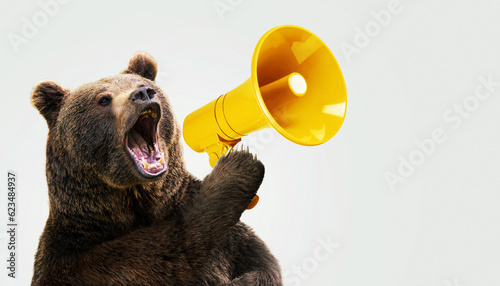 Creative brown bear holds a yellow loudspeaker in paw and shout on a light blue background. Animal cool boss and business management, concept. Creative idea to attract attention. Aggressive marketing.