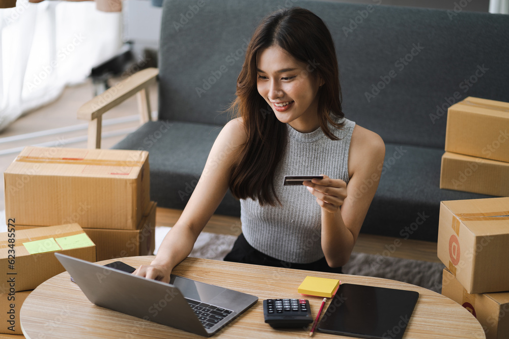 Asian woman holding credit card and using laptop. woman working at home. Online shopping, e-commerce, internet banking, spending money, working from home concept. Asian woman holding credit card and using laptop. woman working at home. Online shopping, e-commerce, internet banking, spending money, working from home concept.