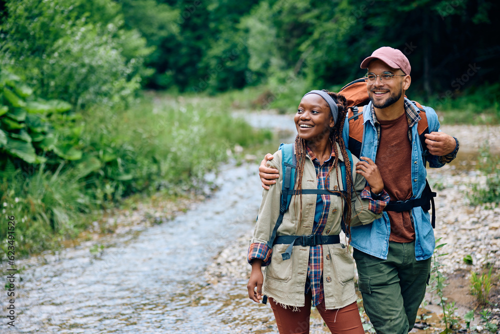 Happy couple with backpacks embracing while hiking in nature.