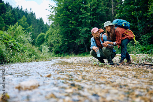 Happy couple of hikers enjoying by mountain river.