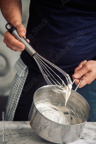 Photos chef holding a white béchamel sauce on a whisk