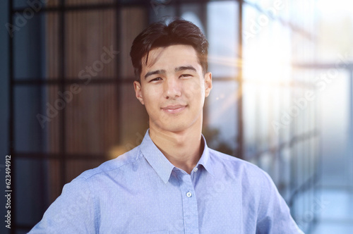 Close up portrait of young asian businessman standing in empty office