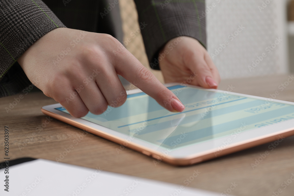 Electronic signature. Woman using tablet at wooden table, closeup Electronic signature. Woman using tablet at wooden table, closeup