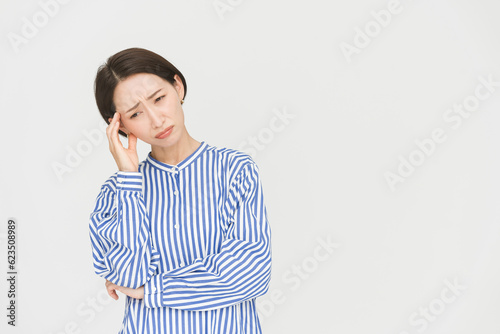 Foto こめかみに手をあてているミドル世代日本人女性/頭痛