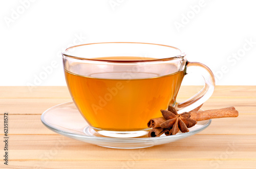Glass cup of green tea with cinnamon sticks on wooden table background.