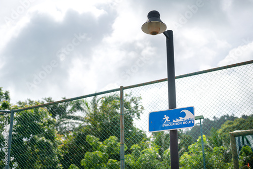 The tsunami evacuation and escape route signpost on cloudy sky background, using as information guideline in the emergency case. Transportation symbol object photo.