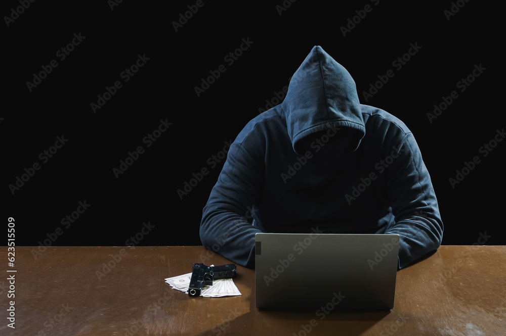 Hacker spy man one person in black hoodie sitting on table looking computer laptop used login password attack security to data digital in internet network system night dark background copy space Hacker spy man one person in black hoodie sitting on table looking computer laptop used login password attack security to data digital in internet network system night dark background copy space