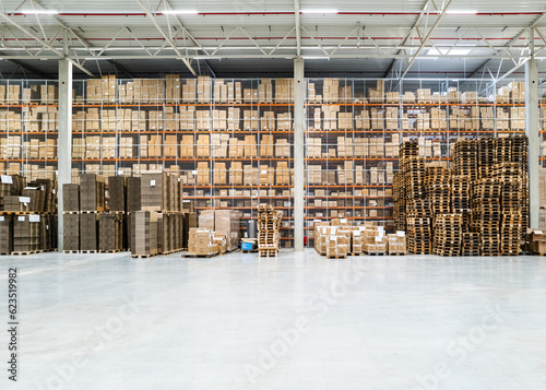 Helle Industrie-Halle mit Hochregal, Kartonagen, Paletten und Verpackungsmaterialien mit größer Freifläche 