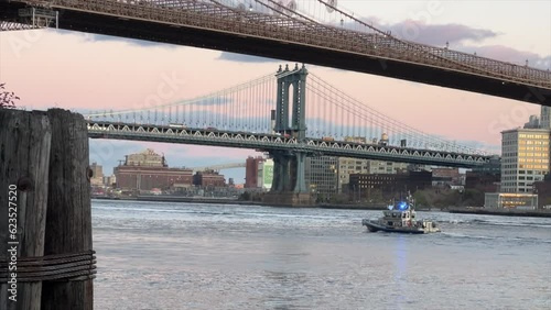 New York, USA - 2023: NYPD police boat at Brooklyn Bridge and panoramic sunset view of downtown Manhattan after sunset. NYPD boat responding to emergency on the East River, NYC. photo