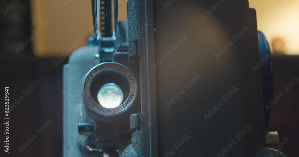 Old Film Projector. An Old Movie Projector Scrolls 8 mm Film with Vintage Video in the Room. Front View of an Old Fashioned Antique 8mm Movie Projector Projecting a Beam of Light in a Room