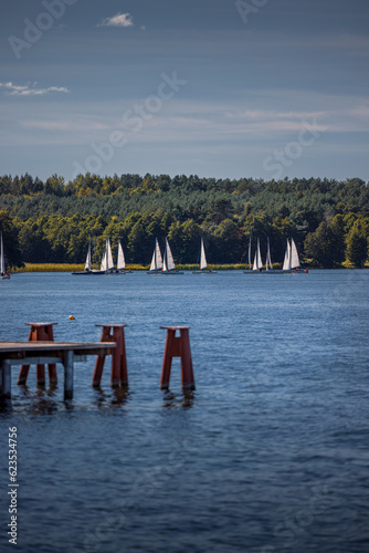 Sailboats on Ukiel lake in Olsztyn. In the foreground, the pier at the city beach