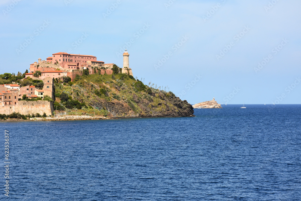 On the Mediterranean coast of Italy, picturesque ancient buildings and an old lighthouse on the background of the sea