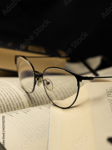 New paperback books, diary, fanned pages on wooden desk table and grunge background Daylight. Books stacking. Back to school. Copy Space. Education background, Reading background, glasses on book.