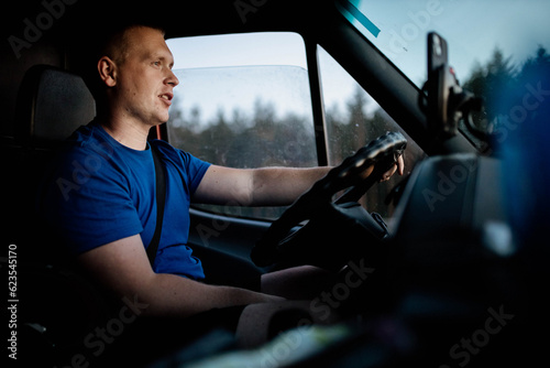 Obraz na płótnie male trucker rides on a sunny day for a trip. Young van driver w salonie