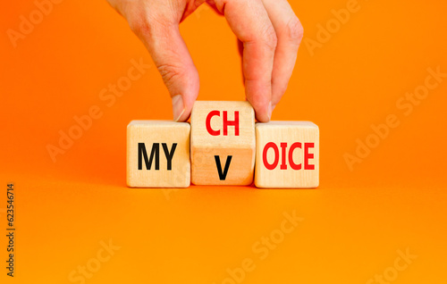 My voice and choice symbol. Businessman turns wooden cubes and changes the concept word my choice to voice. Beautiful orange table orange background, copy space. Business and my voice choice concept.