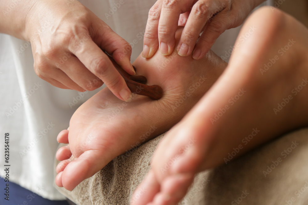 Client receiving acupressure reflexology treatment with wooden points massager stick. Natural medicine, reflexology, acupressure foot massager oppresses energy flow points Client receiving acupressure reflexology treatment with wooden points massager stick. Natural medicine, reflexology, acupressure foot massager oppresses energy flow points