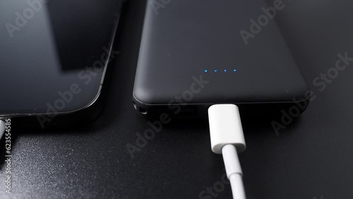 Power bank for charging mobile devices on a black background. Smartphone charger with power supply. External battery for mobile devices.