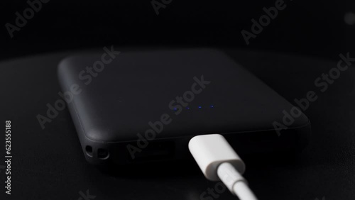 Power bank for charging mobile devices on a black background. Smartphone charger with power supply. External battery for mobile devices.