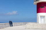 Vista de una pareja de turistas mirando al mar desde un faro en las costas españolas.