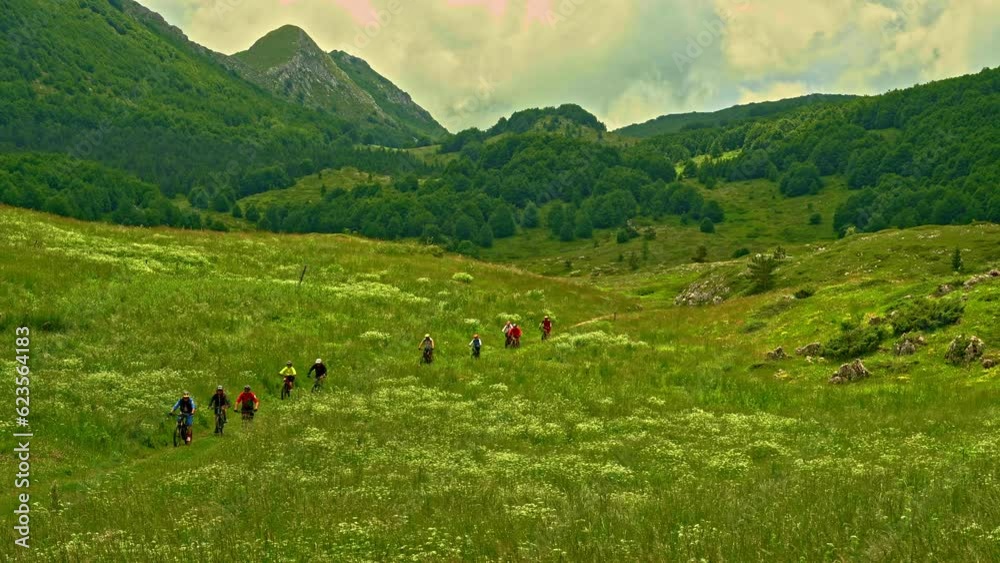 A group of bikers cross the meadow in one of the green valleys in the Gran Sasso and Monti della Laga National Park. Abruzzo, Italy, Europe