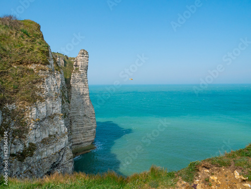 White cliffs of Etretat, Normandy, France, with stunning view of the emerald sea ( the channel) and the blue sky in the background