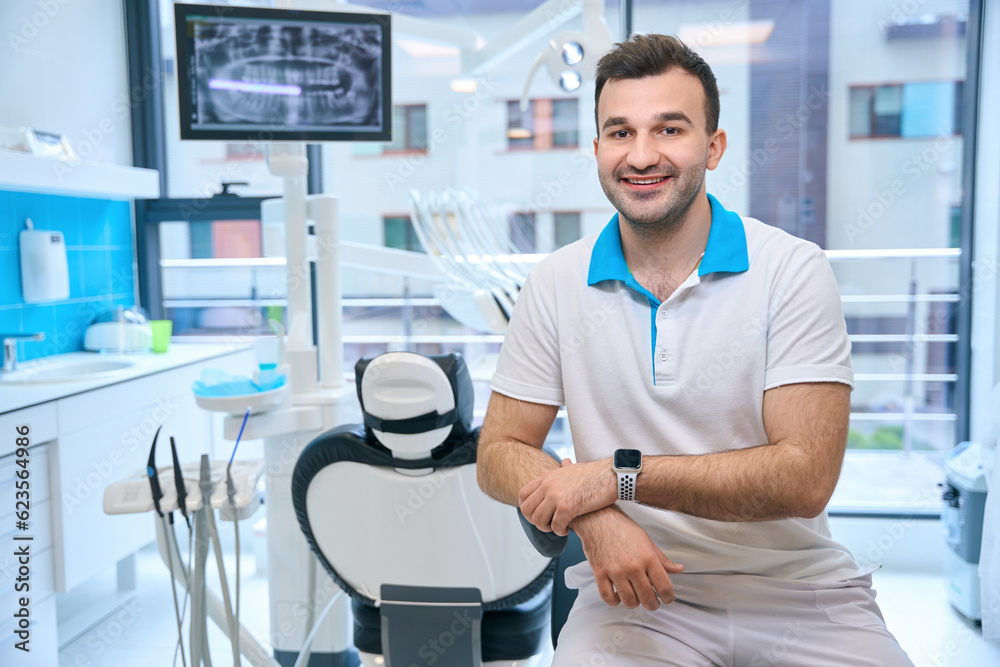 Fototapeta premium Smiling man sitting at the workplace in the dental office