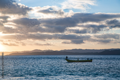 Lonely boat at sunset over the Raja Ampat islands in the Indian Ocean, West Papua, Indonesia photo