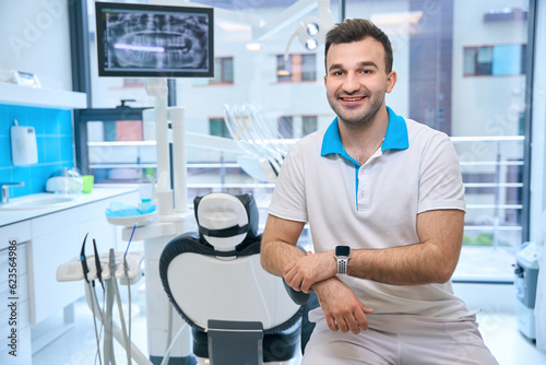 Smiling man sitting at the workplace in the dental office