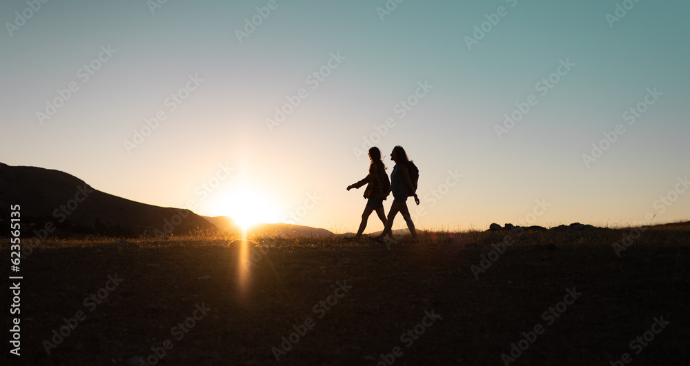 two people walk along a mountain range