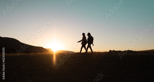 two people walk along a mountain range