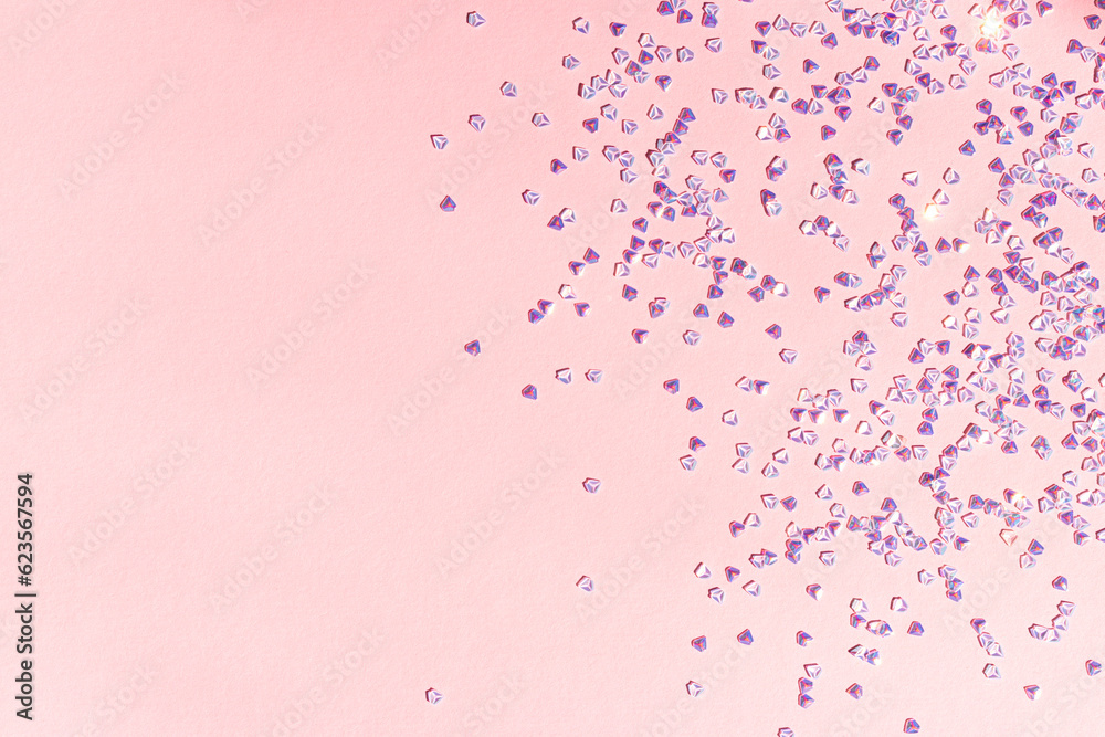 Fototapeta premium Small silver crystal confetti on a pink background. Shiny concept with copy space.
