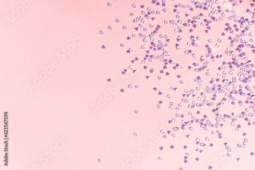 Small silver crystal confetti on a pink background. Shiny concept with copy space.