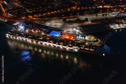 Rostock  Warnemuende  Germany  aerial night view of illuminated cruise ship  Carnival Pride  of Carnival Cruise Line  while leaving cruise port  illuminated Warnemuende city in the background 