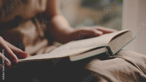 a girl in a vintage dress reads an ancient book at home. female hands turning pages in a book. close up. Woman reading book.