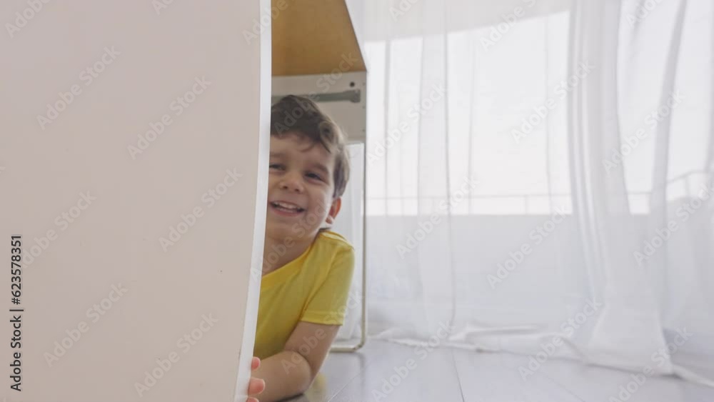 Happy laughing small child playing hide and seek at home Happy laughing small child playing hide and seek at home